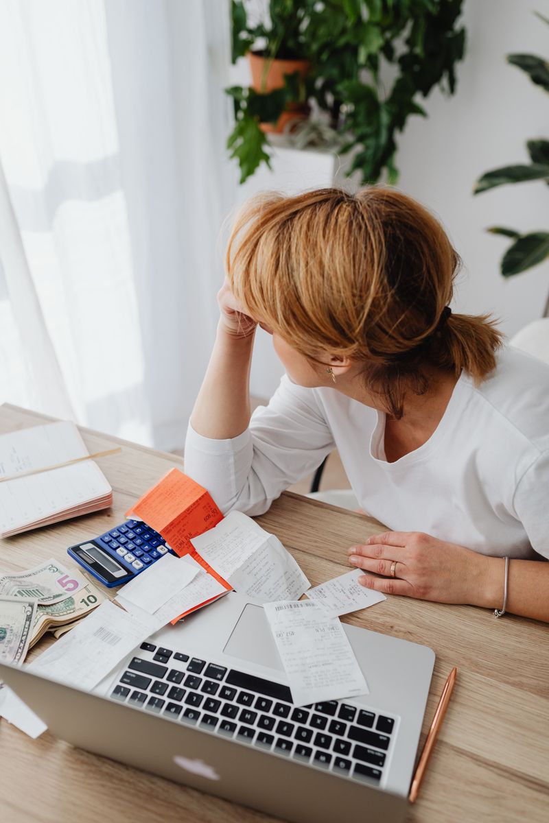 A parent and child reviewing a handwritten grocery list at a kitchen table with reusable bags nearby.